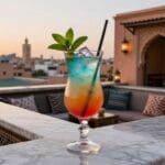 Guida Gastronomica di Marrakech 2 Cocktail colorato servito su un rooftop di Marrakech con vista sulla città al tramonto