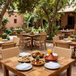 Dove Mangiare a Marrakech: Dai Rooftop Panoramici allo Street Food Autentico 6 Il giardino del ristorante La Famille a Marrakech con tavoli all'ombra degli alberi e piatti vegetariani colorati
