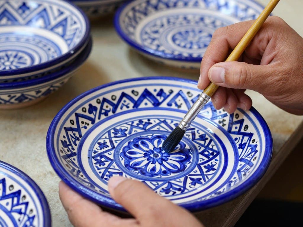Artigiano che dipinge ceramica tradizionale di Fes con motivi blu e bianchi